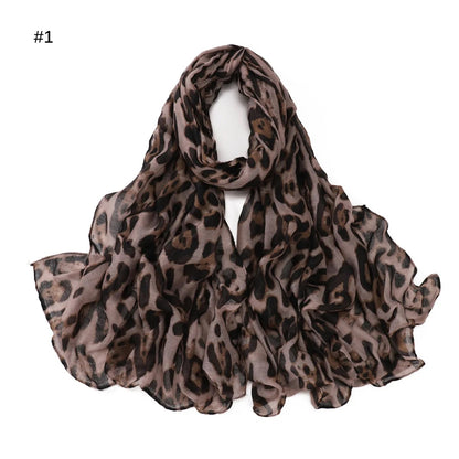 A collection of three leopard print scarves in brown, black, and grey colours, worn by a woman in a brown outfit.