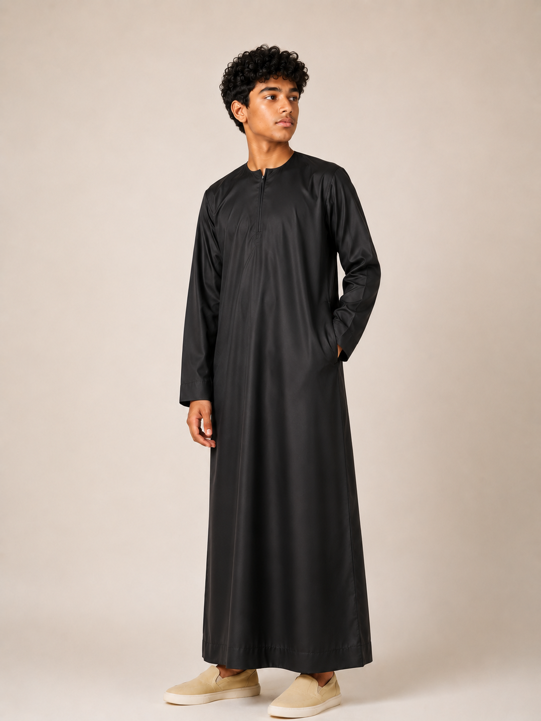 Boy wearing a premium Omani thobe in black featuring a traditional neckline with front zip detail and a relaxed fit.