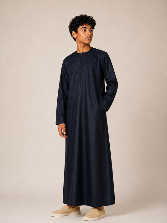 Boy wearing a premium Omani thobe in midnight navy with a traditional Omani neckline, front zip detail and elegant tailored finish.