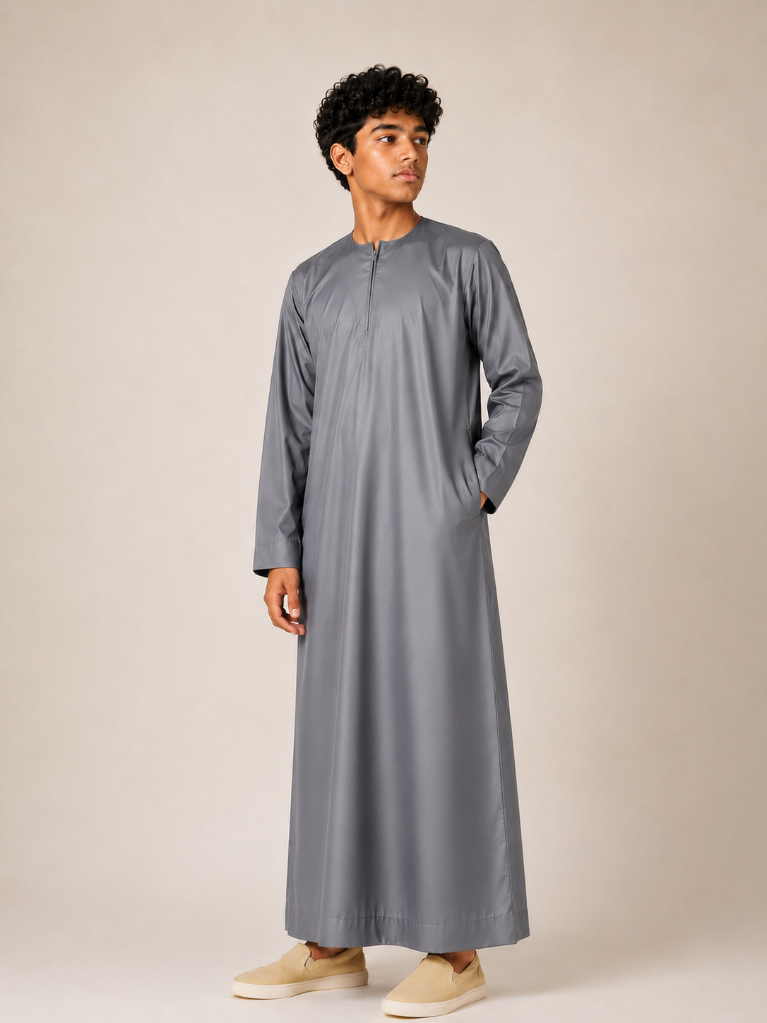 Boy wearing a premium Omani thobe in slate grey with a traditional neckline, front zip detail and comfortable relaxed fit.
