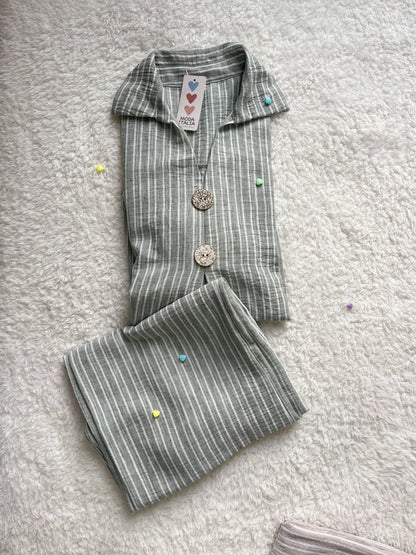 Woman wearing sage green linen co ord set with longline shirt and wide-leg trousers